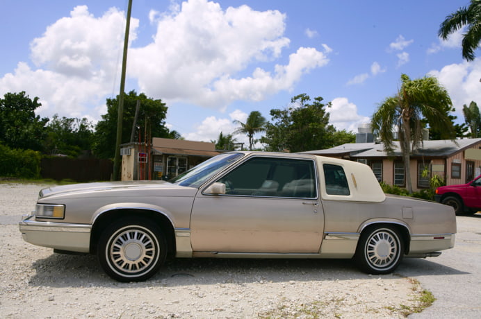 Beige Cadillac on a sunny Texas street with clear skies, illustrating the steps needed to transfer a car title in Texas.