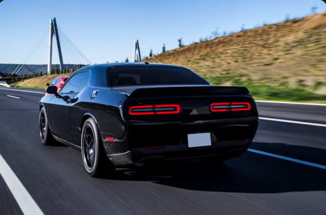 Black Dodge Challenger driving on an Ohio highway, symbolizing the car title transfer process in Ohio.