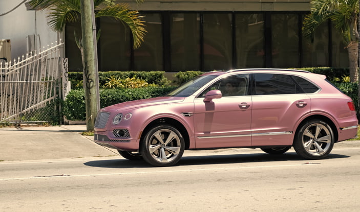 Pink Bentley SUV parked on a California street, representing the car title transfer process in California.