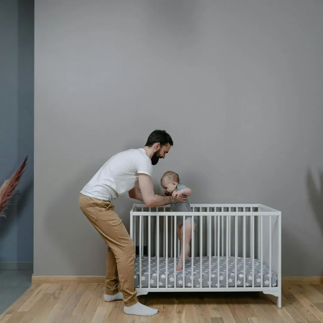 Dad putting his child in a crib