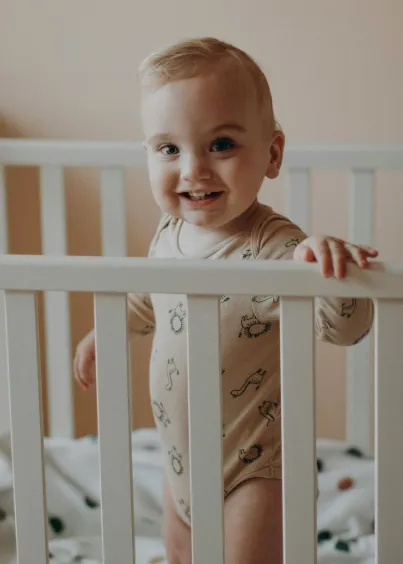 Baby standing and smiling in crib