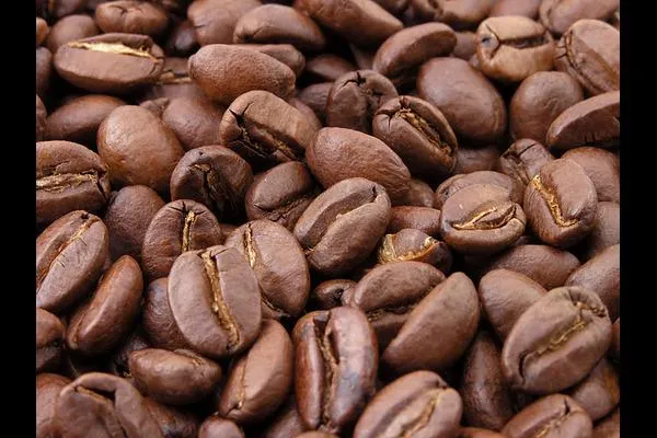Close-up of roasted coffee beans scattered across a surface, symbolizing caffeine and its impact on energy and sleep.