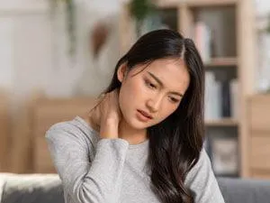 dark haired woman holding neck