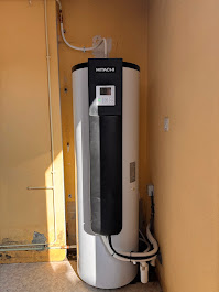 Ballon thermodynamique Hitachi noir et blanc installé contre un mur jaune dans un local technique par AFO Énergies à Saint-Jean.