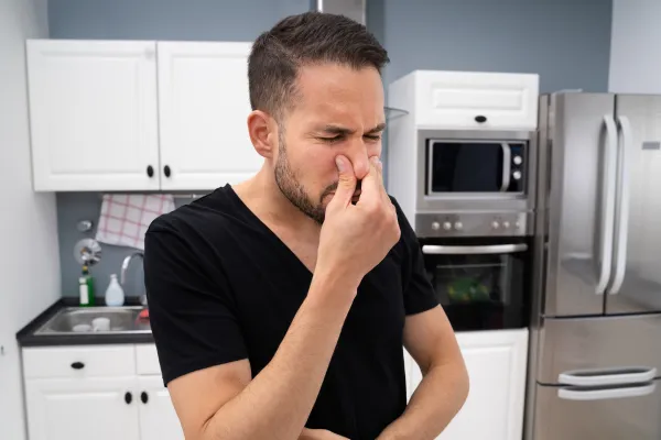 Man covering nose from bad odor in living room — HazWash™ odor removal Detroit