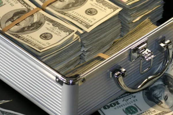 A silver metal briefcase filled with stacks of hundred-dollar bills, representing business cash flow management and financial resources that could benefit from the small plates approach to organize business finances more effectively.
