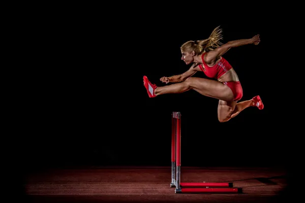 A powerful, dynamic image of a focused athlete (e.g., a marathon runner, a martial artist, a cyclist) sitting in the Mobile Wellness sauna inside a hotel room. They should look determined and in control, conveying a sense of professional dedication to their recovery process.