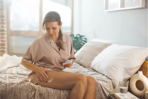 An image of a woman rubbing a cream on her skin.
