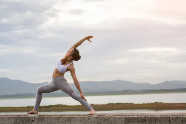 A woman doing yoga next to a body of water