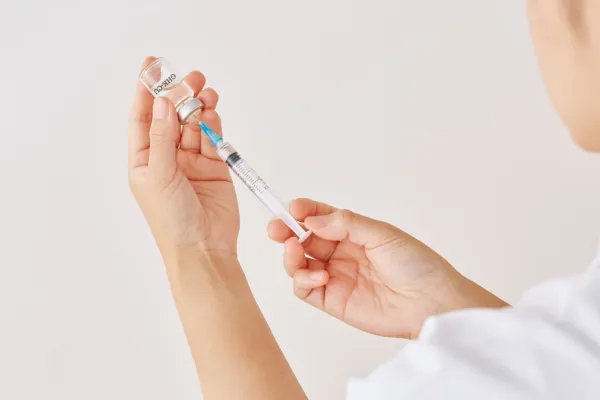 Someone pulling medication out of a clear vial.