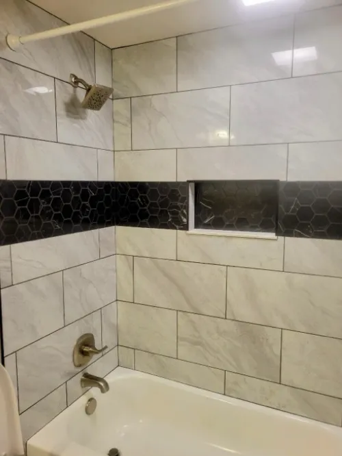 Bathroom remodel with white tile, black hexagon accent, and niche.