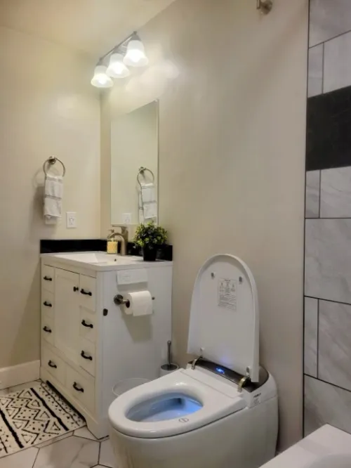 Bathroom remodel with white vanity, smart toilet, and tile accents.