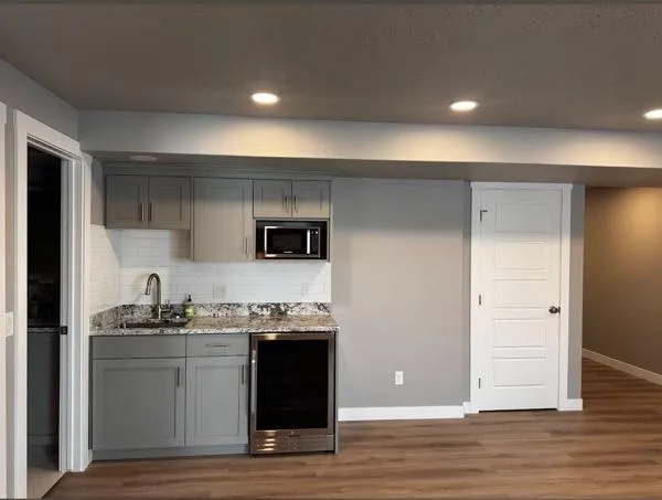 Modern basement kitchenette with gray cabinets and granite countertop in Ogden UT