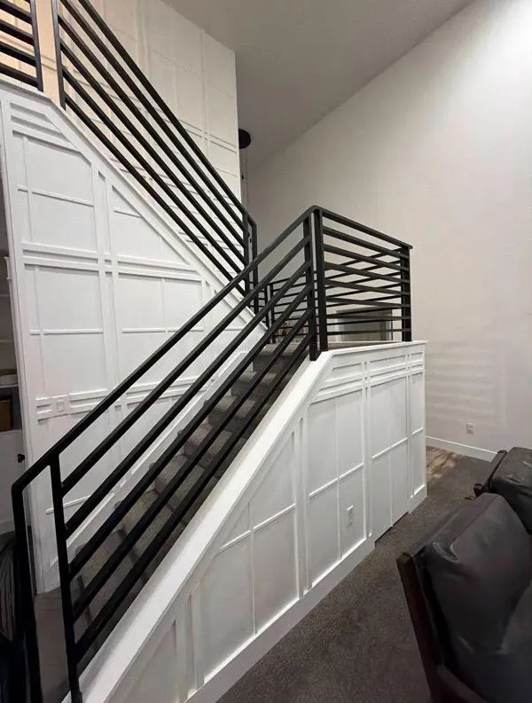 Stylish staircase remodel with black railing and white panel walls in Ogden UT