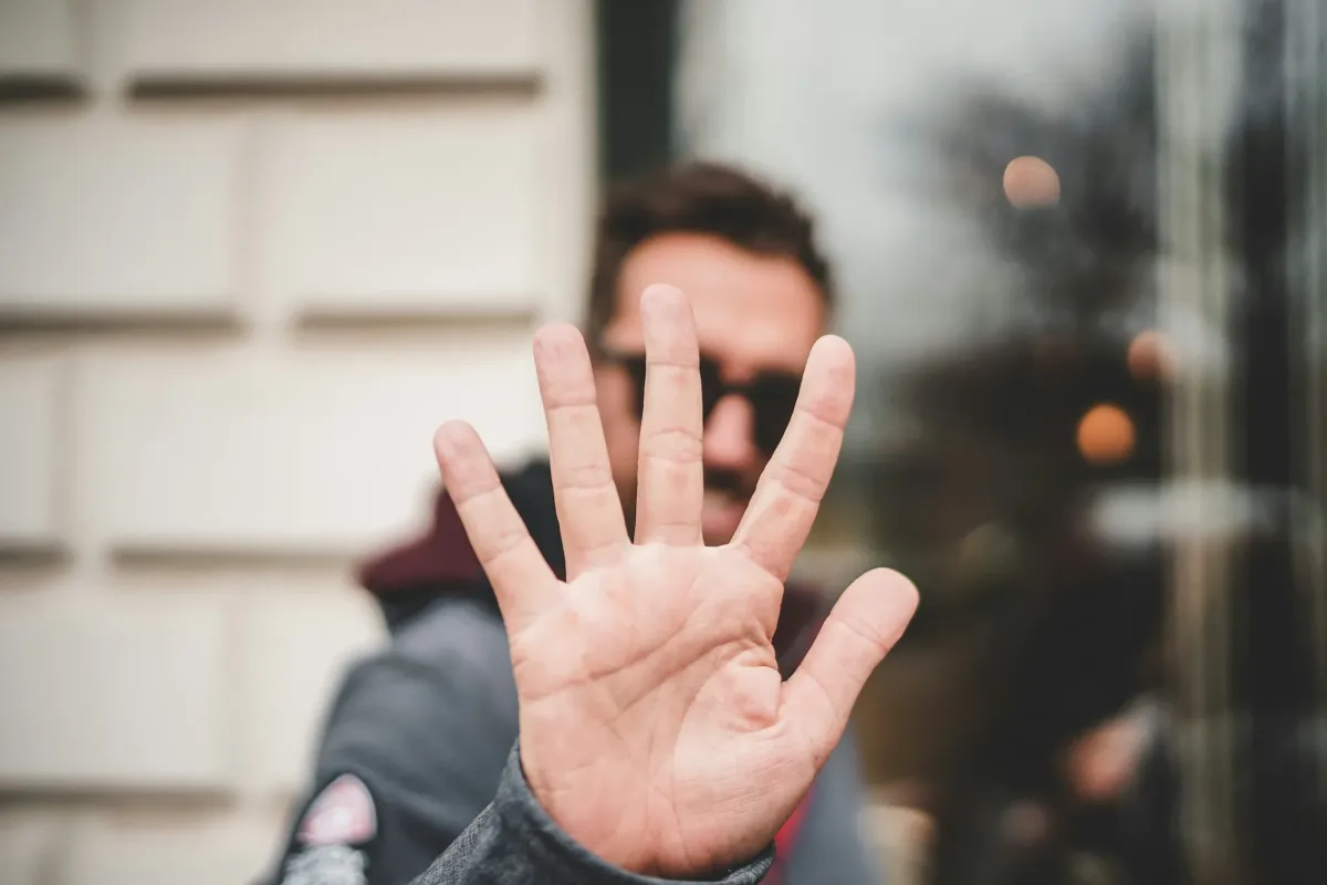 Man standing with one hand covering his face, symbolizing stress, overwhelm, and the emotional challenges of Pathological Demand Avoidance (PDA).
