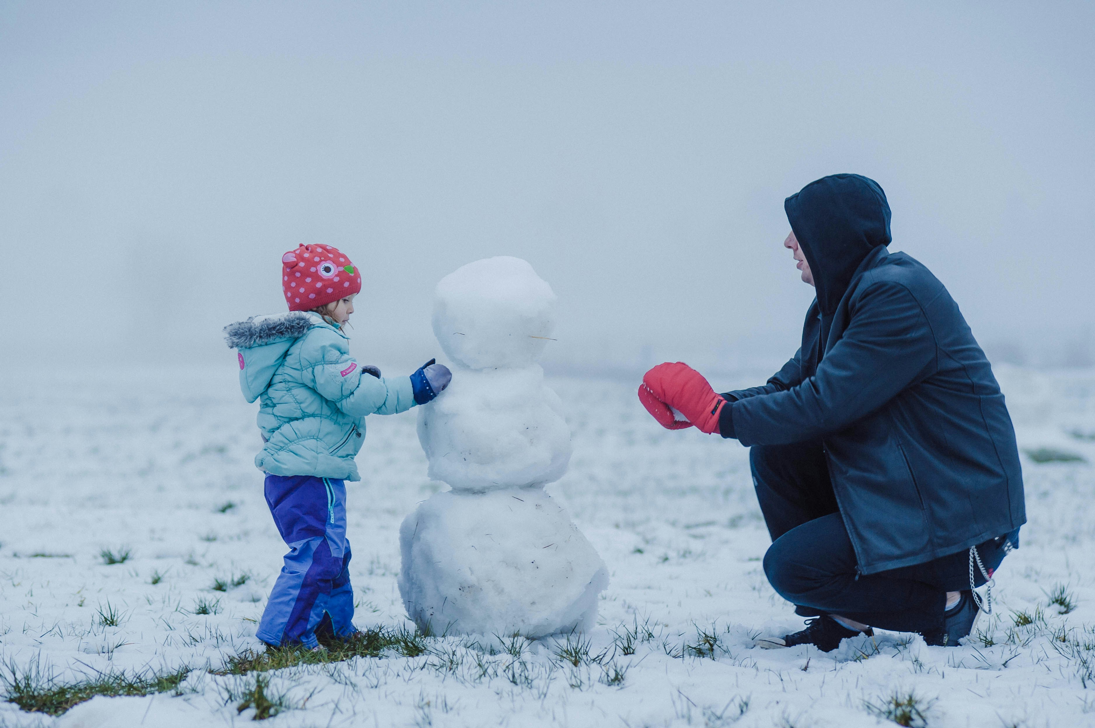 Parent and neurodivergent child in Washington DC going out in the cold and building a snowman to manage holiday anxiety and improve executive function.
