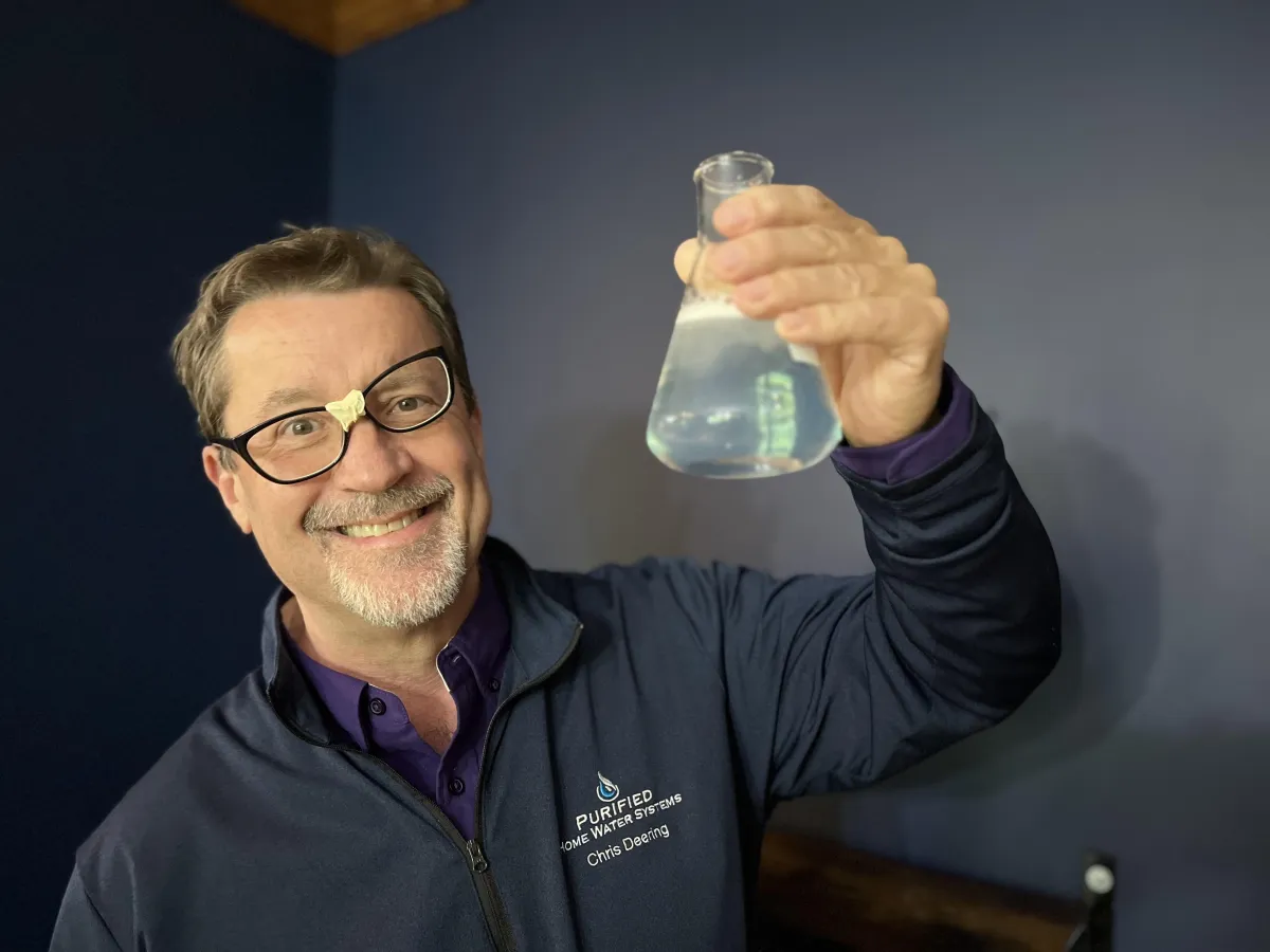 Chris holding up a flask of water, looking like a lovable dork.