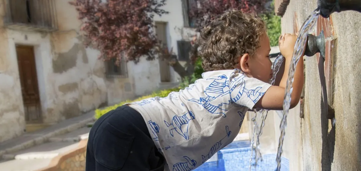 Little boy drinking from an outdoor water faucet