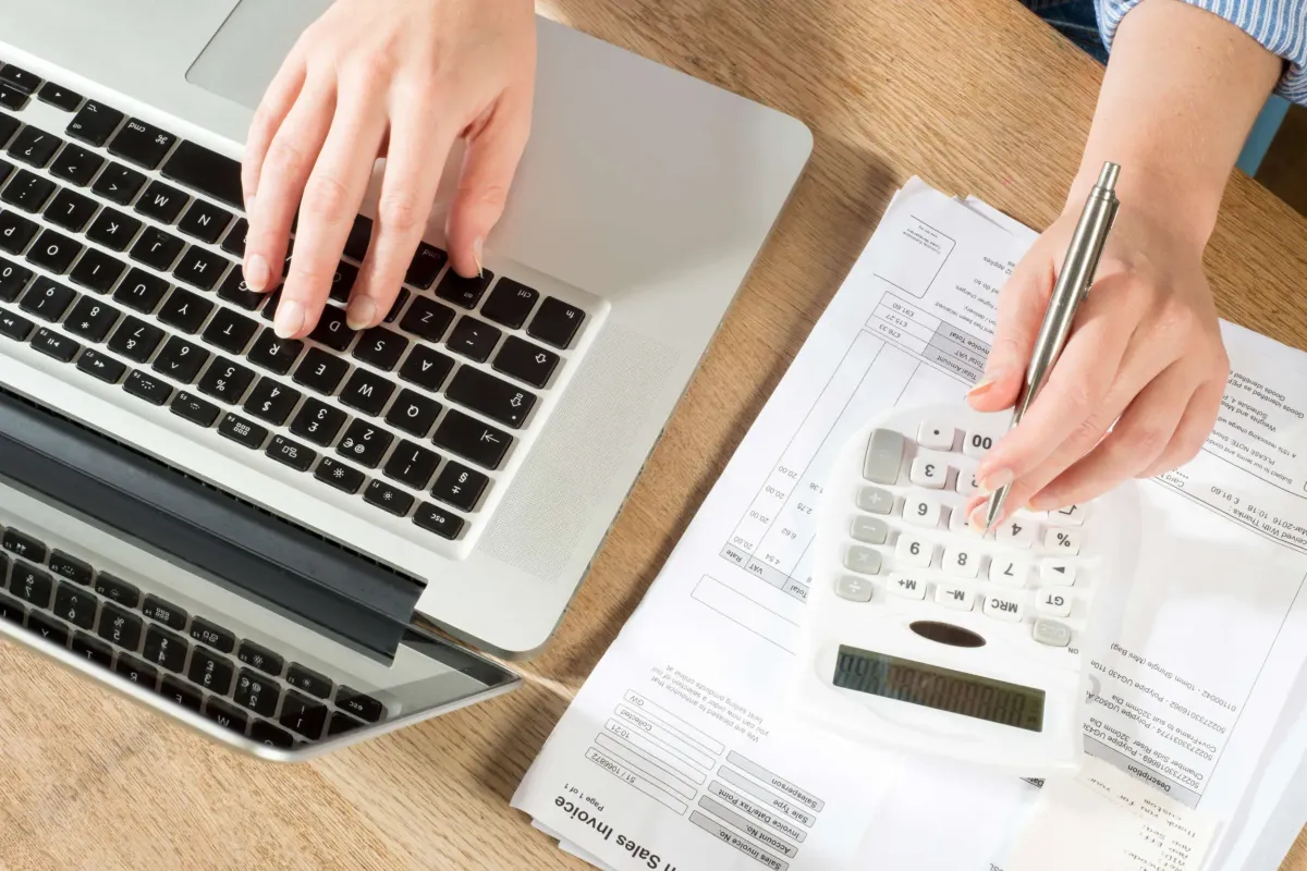 Professional desk setup with a laptop displaying financial software, calculator, and financial reports, symbolizing efficient bookkeeping and business growth