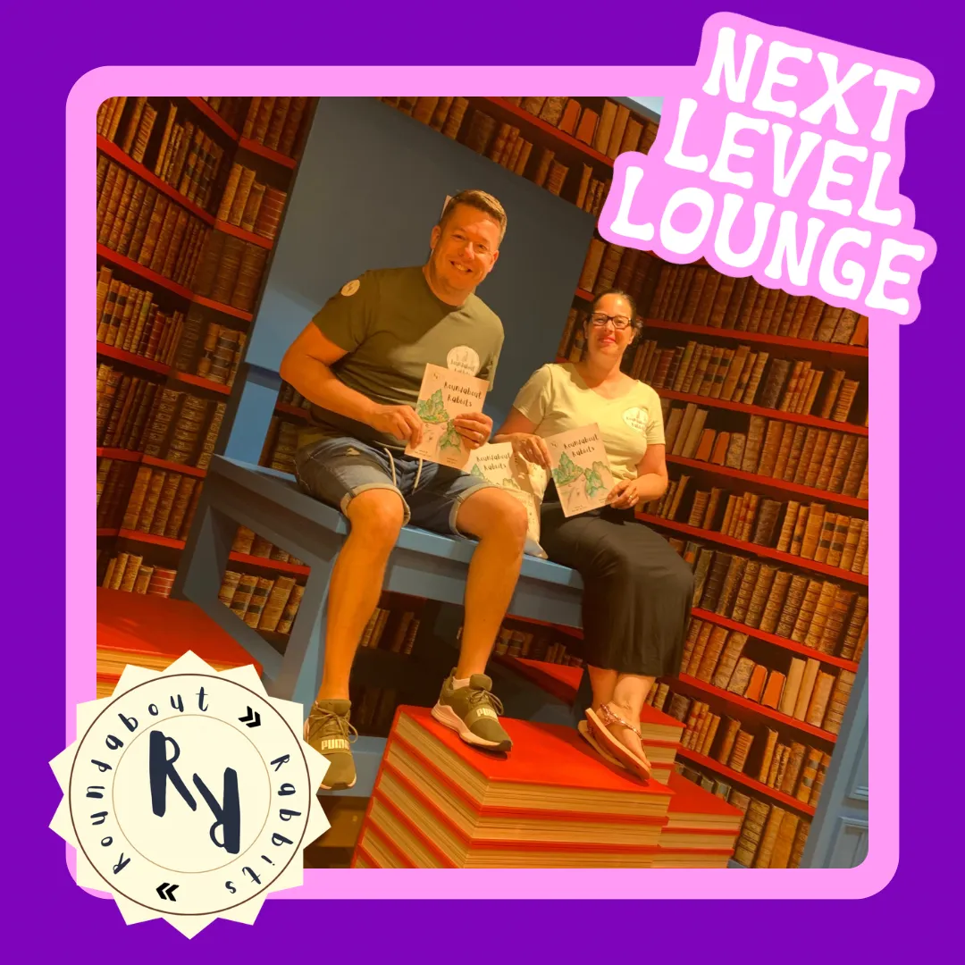 Lisa & Mark Cryer, authors of Roundabout Rabbits, sit together smiling at the camera holding a copy of their book