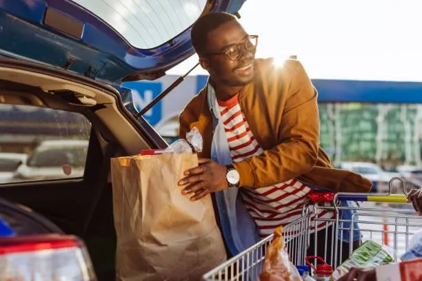 Guy putting groceries in trunk