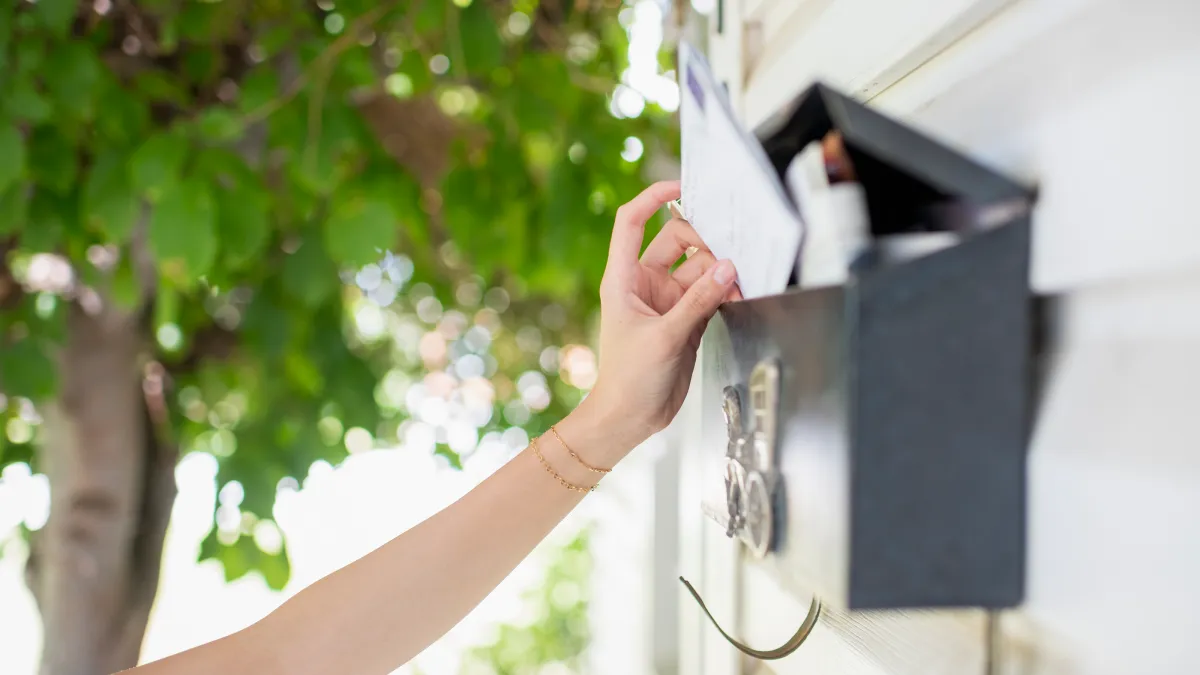 Hand putting mail in mailbox