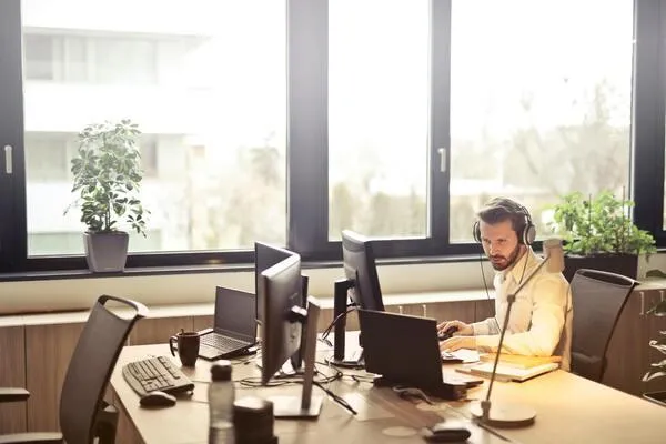 A man with a headset is seated at his computer, actively managing customer follow-up communications.