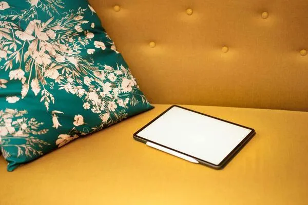 Tablet on a yellow sofa with pillows, representing the inviting space for engaging with blogs that support business success.