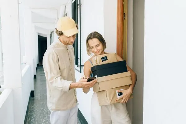 A man and woman examine a phone while holding boxes, representing customer trust in online shopping.
