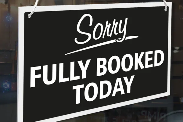 A stylish shop sign on a modern beauty studio door or window that reads "Sorry, Fully Booked," with soft natural lighting and a chic PMU studio in the background. This subtly implies the demand and prestige that PMU Society can help artists achieve.