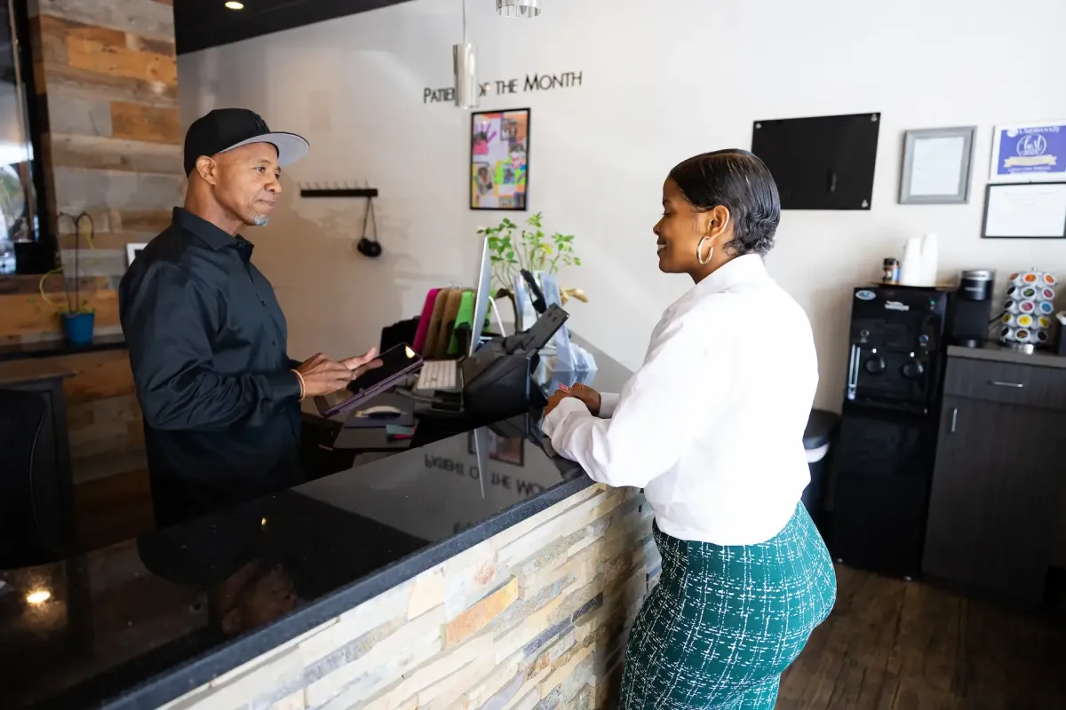 A man speaking with a woman at the front desk of a chiropractic or wellness clinic