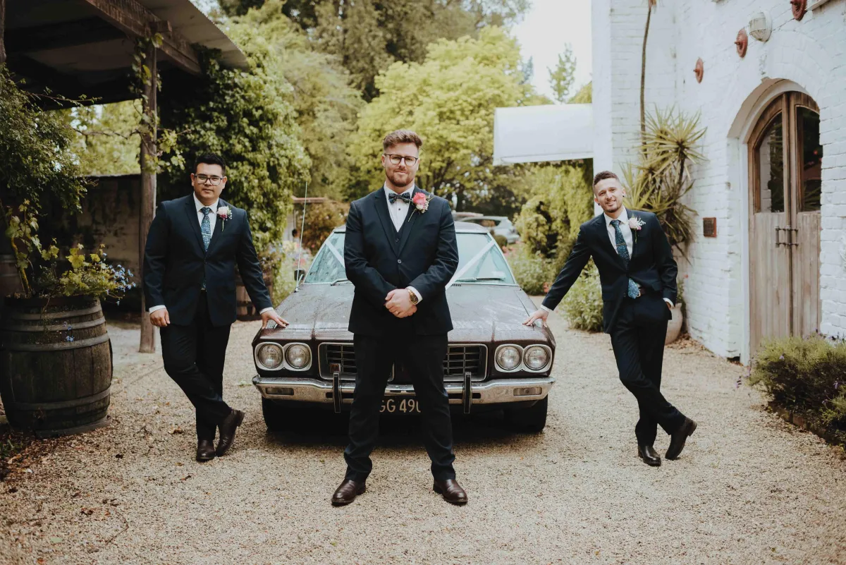 Groomsmen posing with car outside trents vineyard reception venue