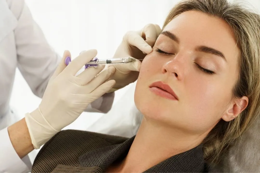 Woman receiving dermal fillers injection at clinic demonstrating treatment process that determines dermal fillers cost.