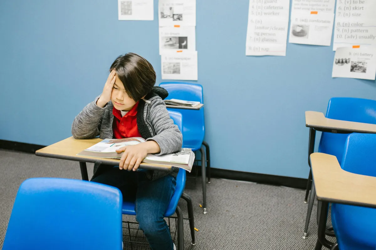 A student sitting alone in a classroom, appearing thoughtful or isolated.