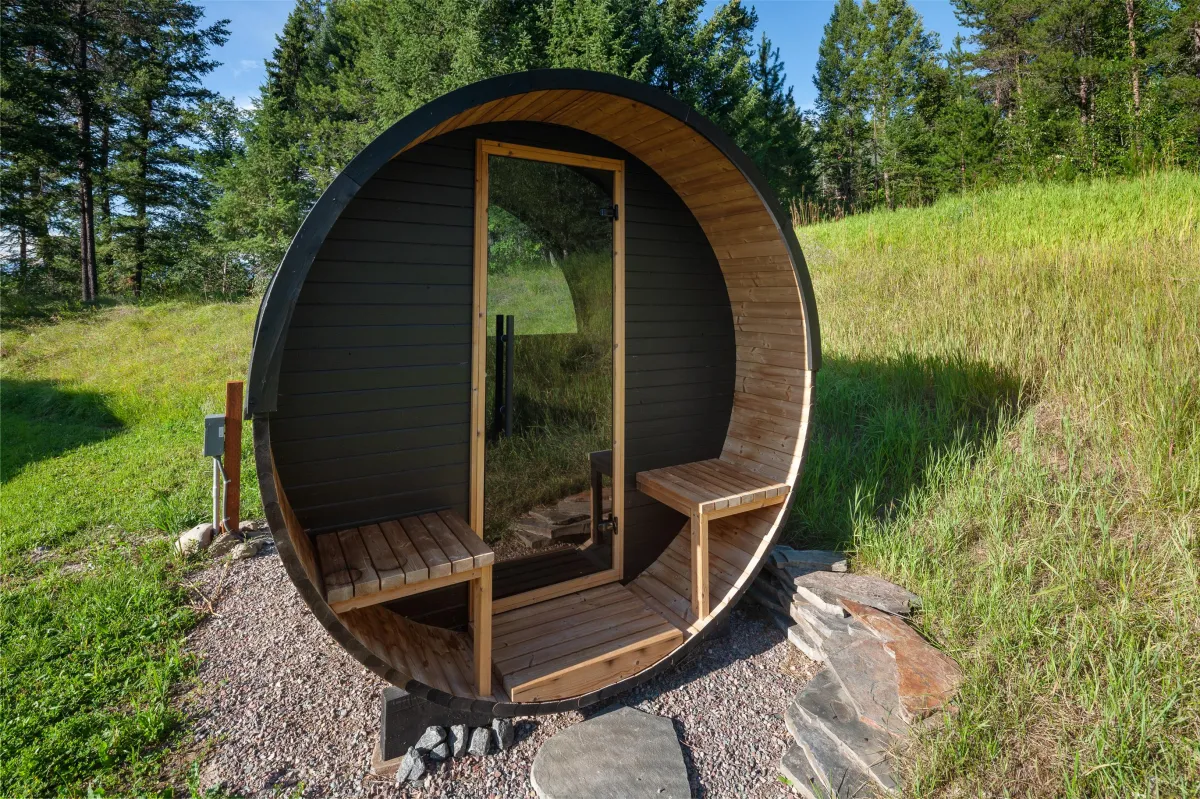 Barrel sauna with seating and panoramic views of the property. A relaxing spot to unwind after hiking, skiing, or exploring Glacier National Park and Montana’s great outdoors.