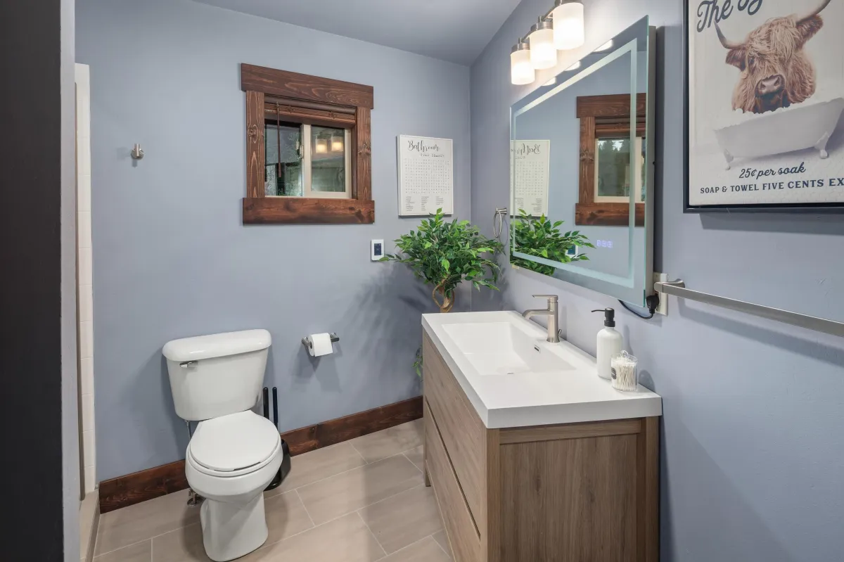 Modern bathroom with single vanity, large mirror, and bright lighting. A comfortable space to refresh after hiking, skiing, or exploring Montana’s Rocky Mountains and Glacier National Park.