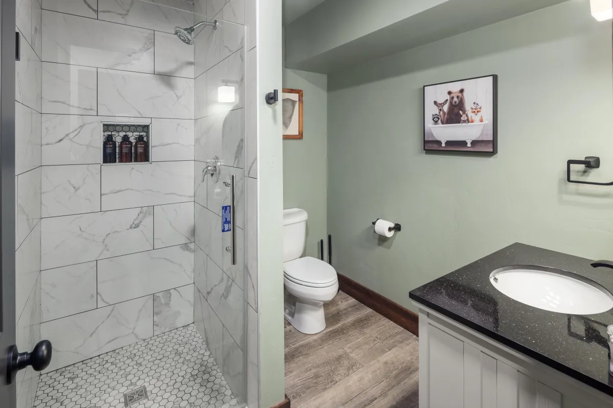 Modern full bathroom featuring a spacious walk-in shower, premium fixtures, and granite vanity. Easily accessible for guests staying in the lower level of this 6BR/5BA luxury Montana lodge near Glacier National Park.