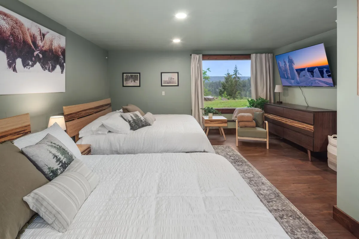 Buffalo room with two king beds, smart TV, and large picture window offering a mountain view. Ideal for families or friends staying in this luxury Montana vacation rental near Glacier National Park.