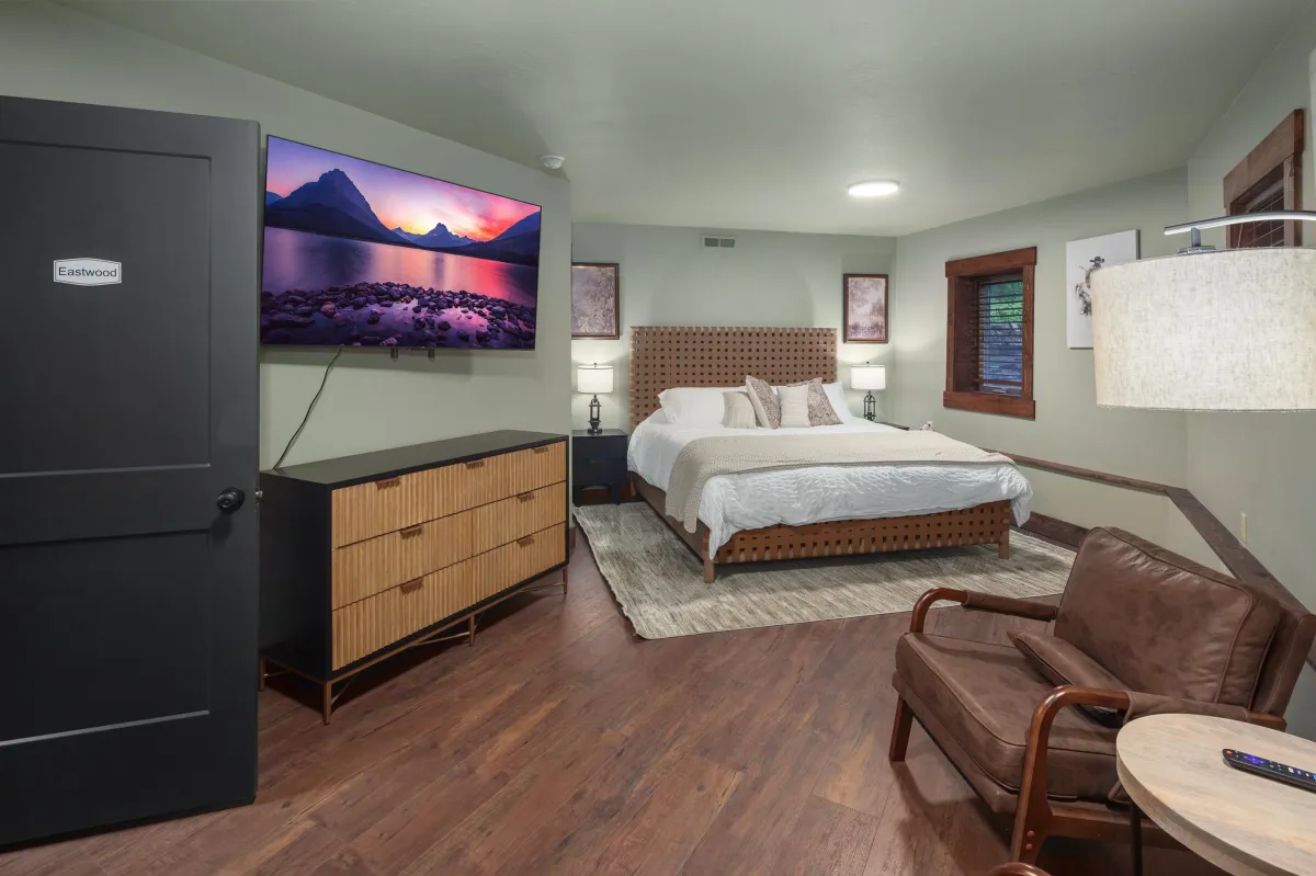 Eastwood room with plush king bed, Western art, seating area, Smart TV, and warm decor. A stylish retreat in this Montana vacation rental minutes from Glacier National Park.