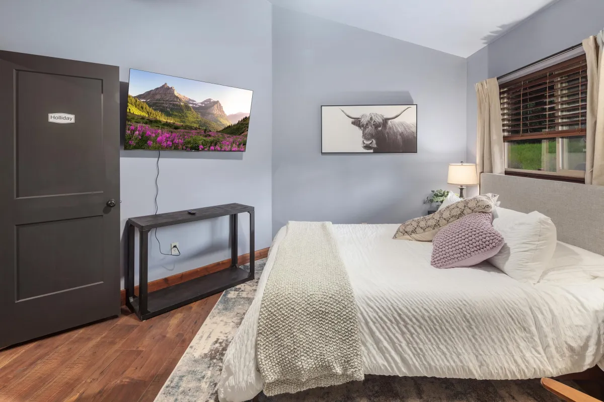 Elegant Western-inspired bedroom featuring a queen bed, rustic-modern decor, and ample natural light. Ideal for restful nights during your Montana adventure near Glacier National Park.