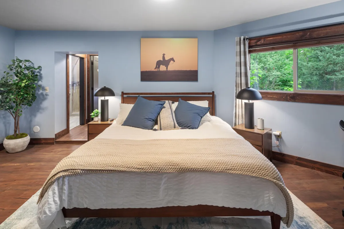 king bed, Western art, and windows overlooking the wooded lot with stunning views of the river and mountains. One of six themed bedrooms in a luxury Montana lodge that sleeps 14, near Glacier National Park.