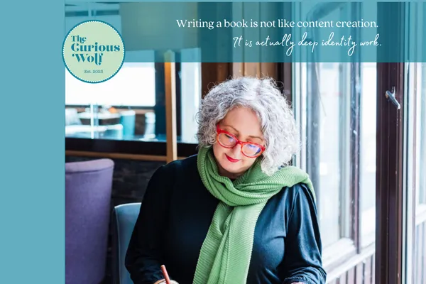 Suzanne Ulph, of The Curious wolf, writing at a desk in front of a window.