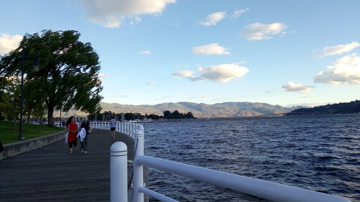 a couple of people walking along the Okanagan Lake boardwalk in Kelowna