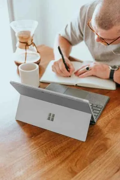 Man sitting at a table writing on a notebook