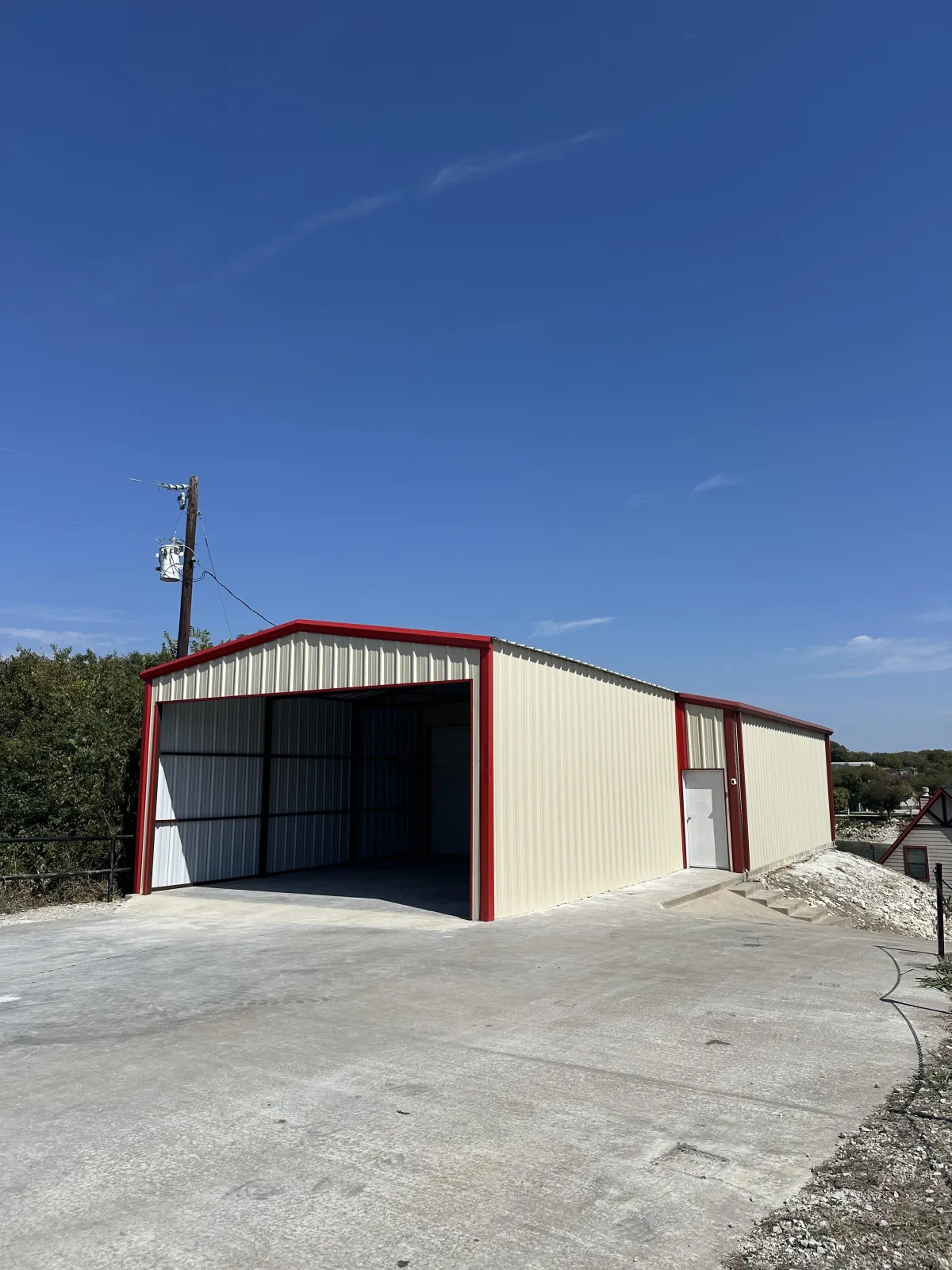 Metal building with roll-up bay — beige panels, red trim.