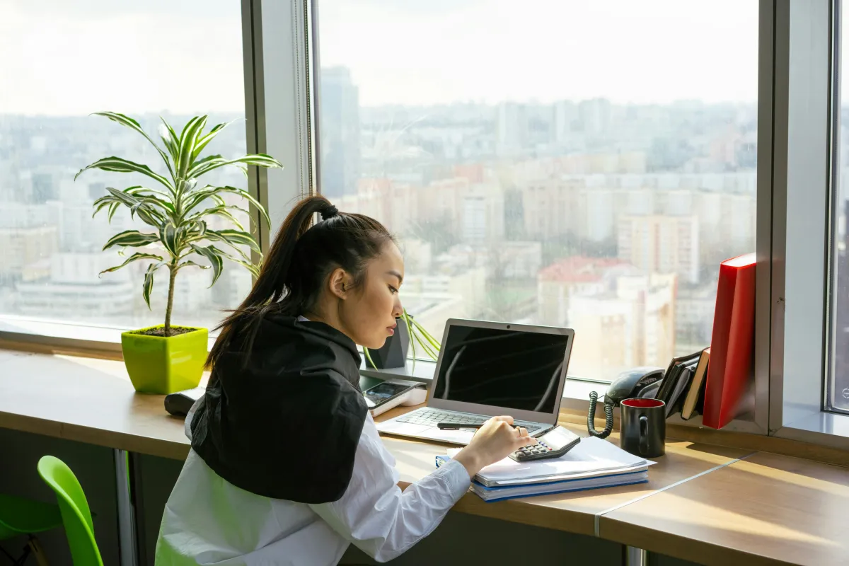 Woman bookkeeping by window with plant