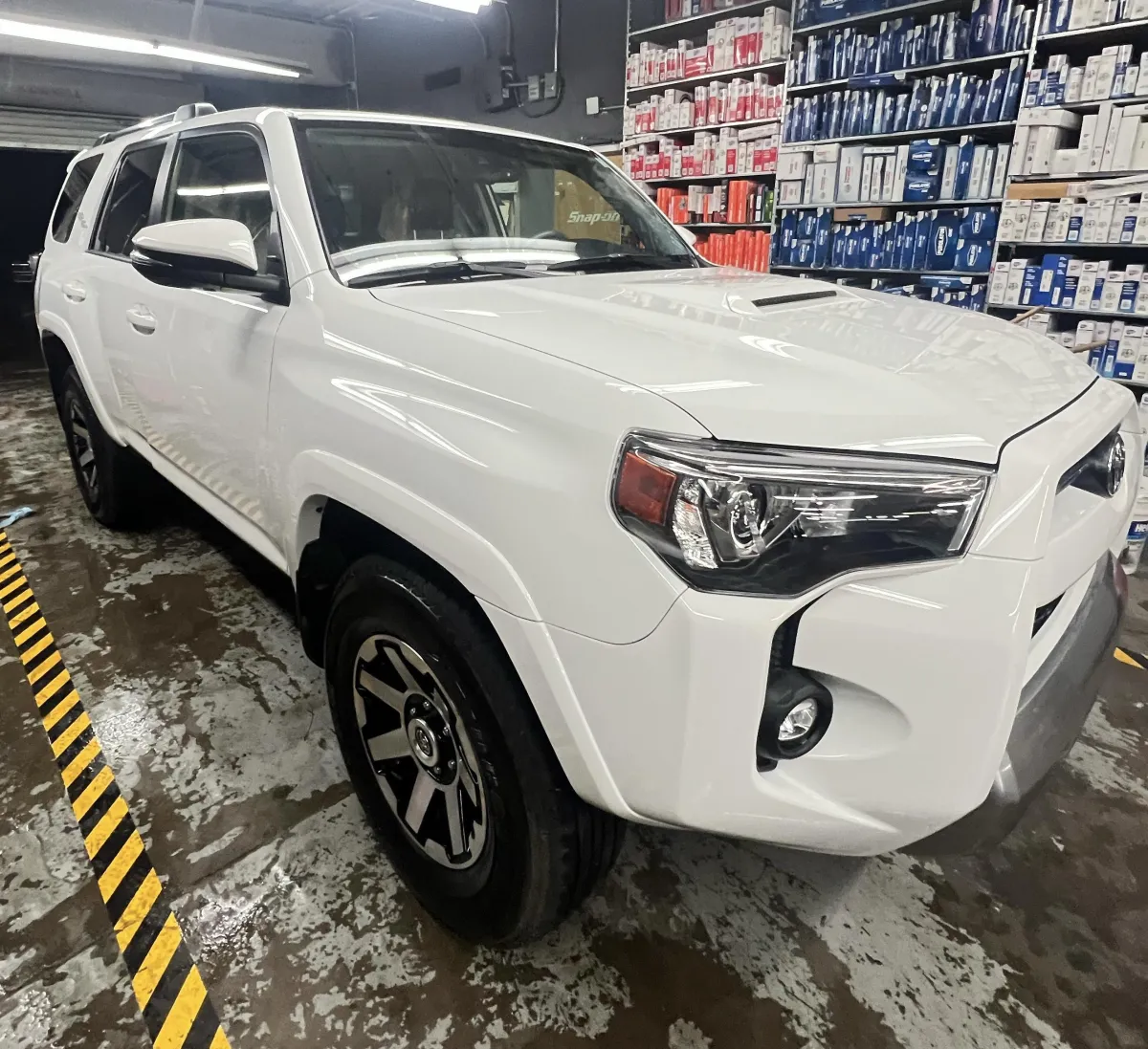 The interior of a car undergoing professional detailing at RND Detailing and Glass Repair. The seats, steering wheel, and floor are covered with protective plastic coverings,