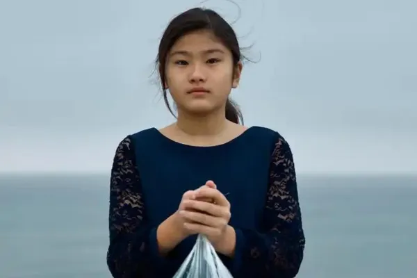 Young girl holding a bag of trash on a beach
