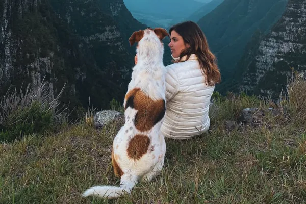 A woman and a dog sitting on a mountain