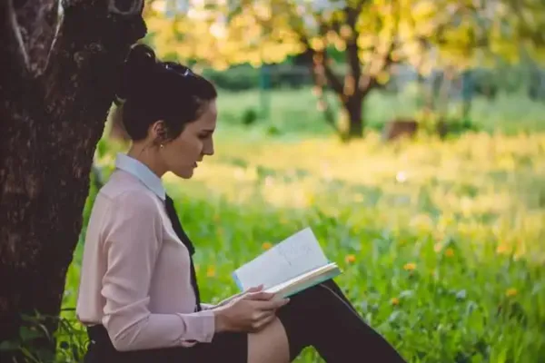 A woman reading a book under a tree